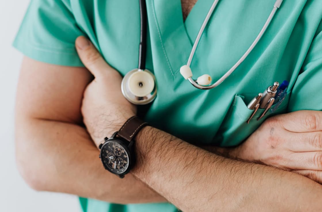 A close-up photo of a healthcare professional in teal scrubs with a stethoscope around the neck