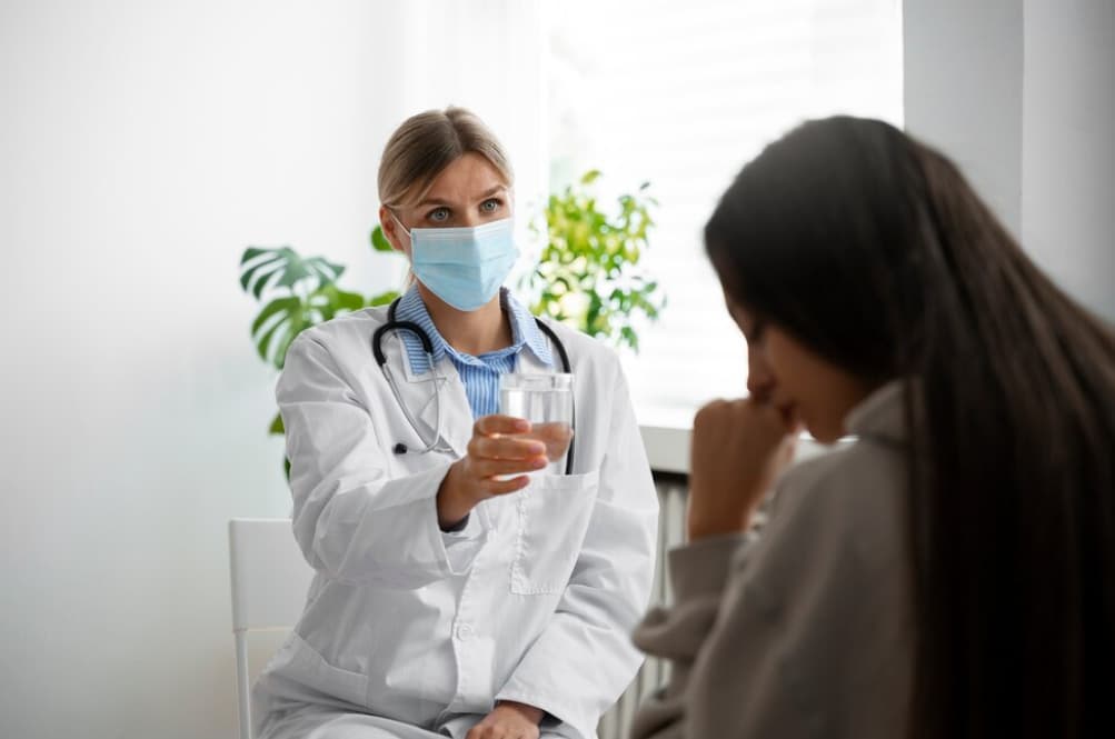 A healthcare professional offering a glass of water to a patient